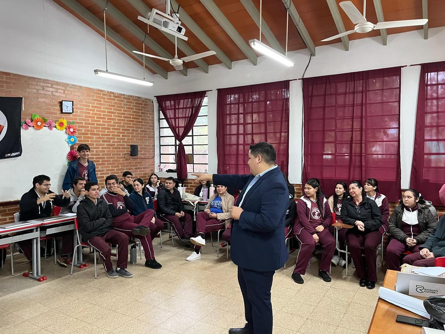 Román Cuyer conversando con jóvenes en un aula